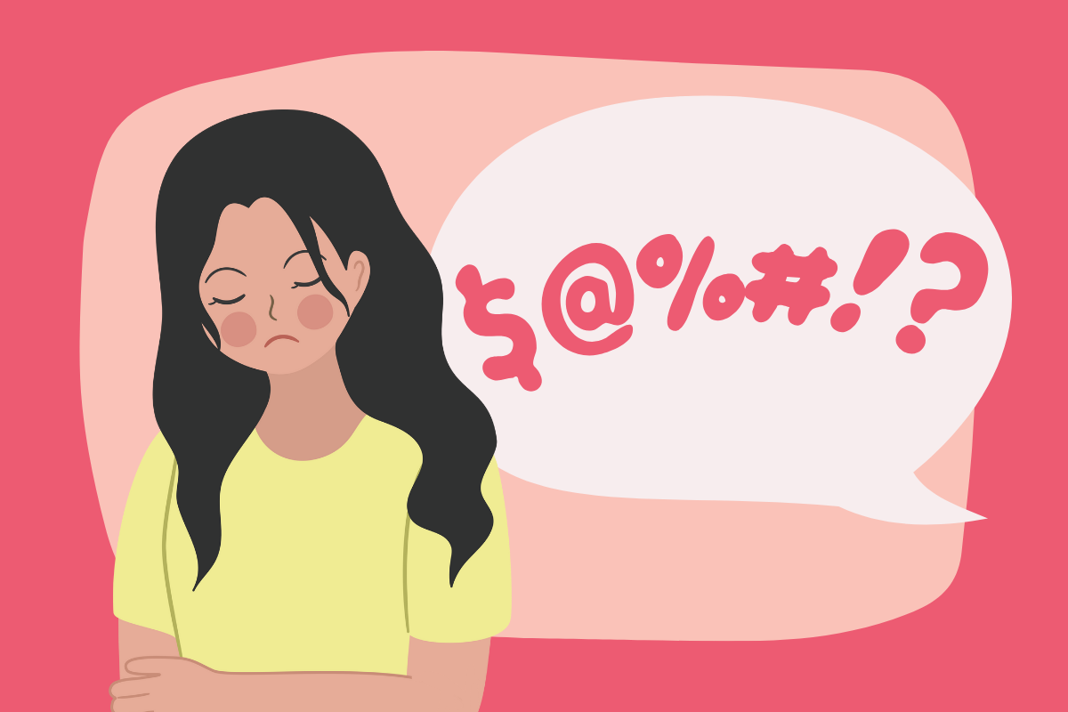 A woman with dark hair and a yellow top being cursed at by a speech bubble of symbols