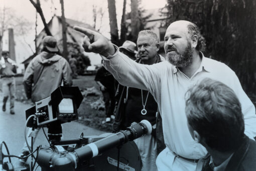 Rob Reiner pointing to something offscreen, a large movie camera is in front of him