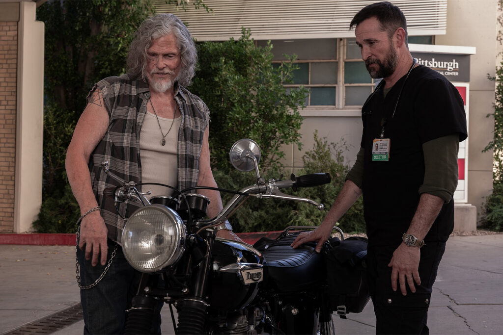 Duke (Jeff Kober) and Dr. Robby (Noah Wyle) checking out a motorcycle outside of the Pitt. Duke's tattoo is visible.